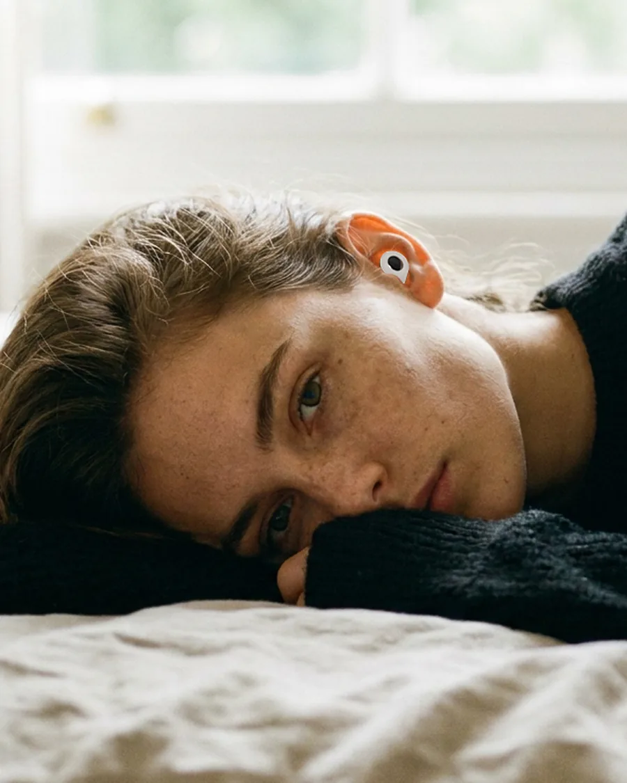 Resting in bed wearing a Noma Earplug at night